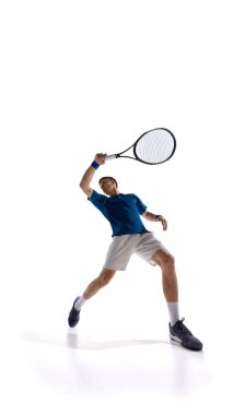 Atletik adam, güçlü servis duruşu olan profesyonel tenisçi, raket yükseldi ve beyaz stüdyo arka planına karşı topa vurmaya hazırlanıyor. Spor anlayışı, enerji salınımı, rekabetçi eylem