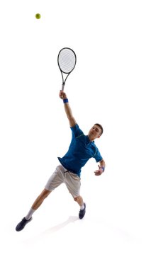 Genç erkek tenis atleti, mavi-beyaz kıyafetli, beyaz stüdyo arka planına karşı topa atlamak için tamamen gerilmiş. Spor anlayışı, çeviklik, rekabet mücadelesi, hizmet anı