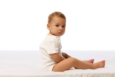 Beyaz elbiseli bir çocuğun omzunun üstünden şüpheli ve ciddi bir ifadeyle baktığı yan görüntü fotoğrafı. Duygu, çocukluk, algı, büyüme, uyanıklık kavramı.