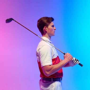 Omuzları boyunca golf sopasıyla duran bir adamın yan görünüş portresi, sakin ve kendine güvenen bir vücut, neon ışığı altında, gradyan stüdyo arka planına karşı durmaktadır. Spor anlayışı, hobi