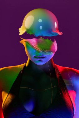 Üç boyutlu kolaj, kadının sıvı desenli holografik kaskı, neon renkli ve soyut hatları olduğunu gösteriyor. Gelecekteki moda, sentetik güzellik ve sanal kimlik kavramı.