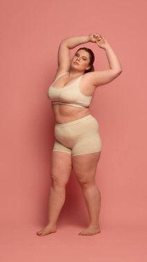 Kendine güvenen bir kadın rahat iç çamaşırlarıyla poz verir, vücut pozitifliği ve çeşitliliği kucaklar. Kendini sevme ve kabullenme kavramı.