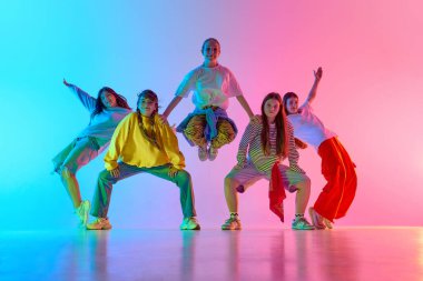 Genç bir dans ekibi rengarenk bir şehir gösterisinde çeşitliliği ve yaratıcı hareketi kutluyor. Dinamik çeşitlilik kavramı ve şehir dans kültürü ifadesi.