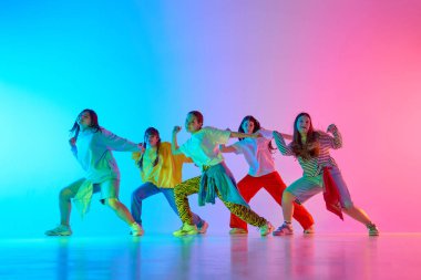 Genç bireylerden oluşan çeşitli bir dans ekibi canlı ve renkli bir sahnede kentsel yaratıcılıklarını enerjik bir şekilde ifade ediyor. Modern dans çeşitliliği ve sanatsal ifade kavramı.