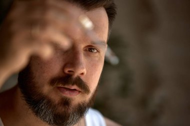 Melez cilt bakımı. Orta yaşlı beyaz bir adam, doğal ışık altındaki küçük bir nesneyi yoğun bir şekilde inceler. Titiz gözlem ve detaylara dikkat kavramı.