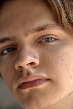 Deri gerçekçiliği. Erkek derisinin yakın çekimi, görünür gözenekler, hafif sakal, alnında parlaklık. Doğal güzellik kavramı, filtre yok, erkek derisi.