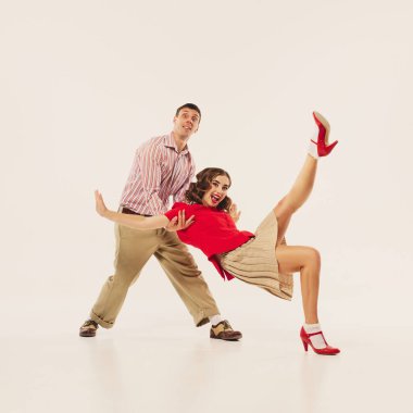 Klasik tarzda bir çift, enerjik bir şekilde beyaz arka planda lindy hop dansı yapar. Geçmişe dönük olaylar ve klasik dans stilleri kavramı.