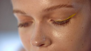 Dopamin makyajı. Kalın sarı göz kalemi ve açık tenli doğal makyajlı bir göz. Yaratıcı makyaj eğilimleri ve güzellik yeniliği kavramı.