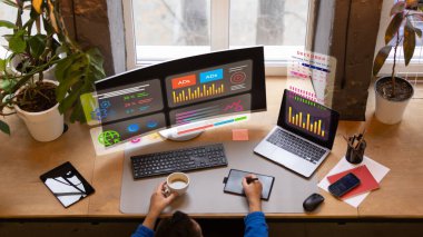 Kıvrımlı monitör, dizüstü bilgisayar ve holografik bilgilerle çalışan yaratıcı dijital analistin en üst görüntüsü. Akıllı iş ortamı kavramı, yaratıcı ekonomi çalışma alanı