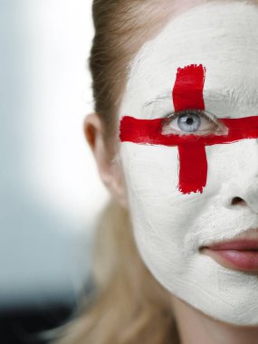 İngiliz bayrağıyla boyanmış bir yüz, ulusal gurur ve canlı sivil kimliği sembolize eder. Vatanseverlik ve kültürel kutlama kavramı.