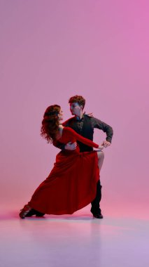 Arjantinli tango dansçıları pembe ve mor sahne ışıklarının altında çarpıcı bir duruş sergilerler, zarafet ve hassasiyet yayarlar. Dansta tutku ve zarafet kavramı.