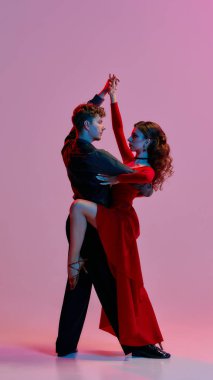 Sofistike bir çift, Arjantin tango dansı pozunu hafifçe aydınlatılmış bir odada veriyor. Kültürel ifade ve duyguyu dans sanatı yoluyla resmediyor..