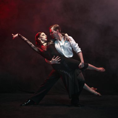 Zarif dansçılar, sisli ve loş bir arkaplana karşı yürekten bir Arjantin tangosunu infaz ettiler. Dans sanatı yoluyla derin duygu ve kültürel hikaye anlatma kavramı.