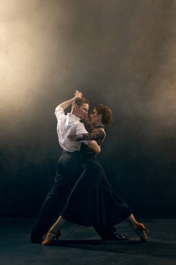Arjantinli tango dansçıları tutkulu bir tango ile sahne ışıkları altında dramatik bir poz veriyorlar. Sahne sanatları fotoğrafçılığında tutku ve yaratıcılığın bir temsili..