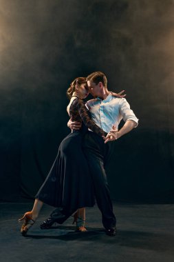 Zarif bir çift Arjantin tangosunu ustaca aydınlatılmış bir sahnede, uzmanlıklarını ve zarafetlerini sergileyerek dans ediyor. Dans sanatında tutku ve ritmin bir temsili..