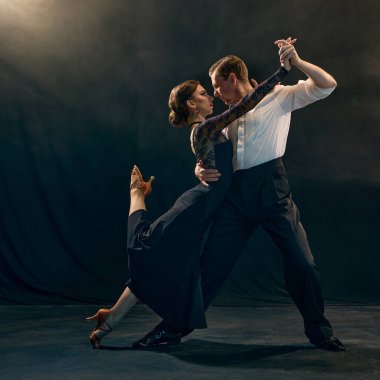 Bir ikili, Arjantin 'in büyüleyici bir tango pozuna sahne ışığı altında vuruyor, zarafet ve yoğunluk sergiliyor. Tutkulu dans ve kültür mirası kavramı.