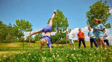 Çocuklar dışarıda güneşli bir gökyüzünün altında takla atarak neşe ve özgürlüğün özünü yakalıyorlar. Çocukken mutluluk fikri ve dışarıda oynamak..