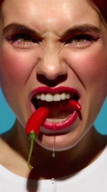 Yüzünde gergin bir ifade ve damlayan suyla buzda donmuş kırmızı biber ısıran saldırgan bir kadın. Yoğun sıcaklık, rahatsızlık, görsel cesaret ve gerçeküstü bağlamdaki duygusal aşırılık kavramı.