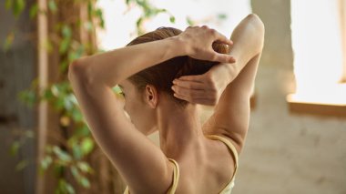 Temiz, tembel melez. Doğal ışıklandırılmış rahat bir iç mekanda sakince saçları güvene alan bir kadın. Sağlık estetiği, kadınsı rutin, sağlıklı güzellik alışkanlıkları, günlük cilt ve saç bakımı kavramı.