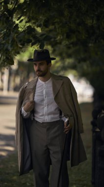 Kaliteli giyinmiş bir adam güneşli bir kaldırımda ağaçların altında yürüyor. Sanatçı konsepti ve eleştiri programları, hikaye tabanlı sanat alanları, zaman tabanlı medya sergileri