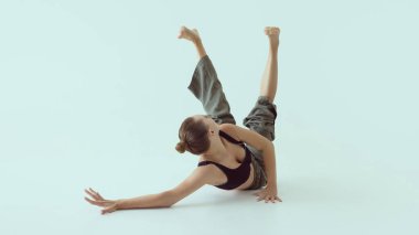 Çağdaş dansçı iki bacağı havada ve yana dönük şekilde yerde kıvrılıyor. Fiziksel kontrol kavramı, etkileyici zemin çalışması, duygusal koreografi ve modern teknik..