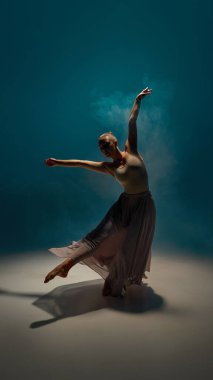 Hareket terapisi. Dönüşün ortasında kolları açık ve sahne ışıkları altında sisli modaya uygun bir model. Tiyatro dansı kavramı, duygu hareket, zarafet ve sahne kompozisyonu..