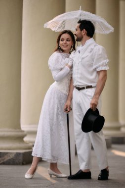 Tarihi kostümler içinde dantel şemsiyelerin altında duran gülümseyen bir çift. Kitap kapağı kavramı, romantik drama posterleri, sanat baskıları, hafıza dergileri....