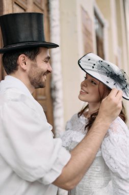 Silindir şapkalı gülümseyen adam, kadın dantel şapkasını nazikçe kaldırıyor. Kitap kapakları, tarihi kurslar görsel, romantik hikayeler, güzel sanatlar..