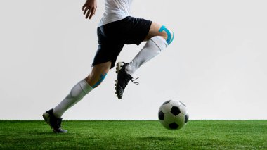 Futbolcu, beyaz üniformalı ve diz bandıyla sahada koşuyor. Spor hareketi, sakatlık desteği, dinamik eğitim, futbol hızlı markalaşma ve gençlik fitness kavramı.