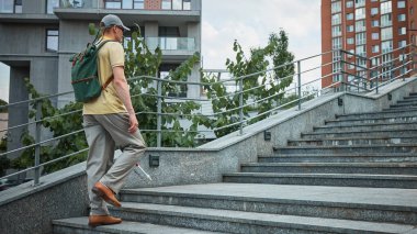Şehir ortamında beyaz bastonlu kör adam merdivenleri tırmanıyor. Sosyal kapsama, şehir ulaşılabilirliği, kentsel hareketlilik, yardımcı navigasyon ve engelli hakları kavramı.