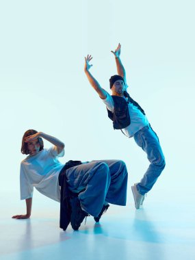 Erkek dansçı geriye doğru eğiliyor ve kollarını kaldırıyor. Kadın partner sabit poz veriyor. Gençlik ifadesi kavramı, dans eğitimi, yaratıcı markalaşma, sağlık kampanyaları.