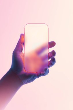 Fütürist sıvı cam tasarımı ve pürüzsüz yansıması olan, puslu pembe arka planda ayarlı, el ele tutuşan akıllı telefon. Teknoloji kavramı, yenilik, minimalist dijital estetik ve yaratıcı reklamlar..