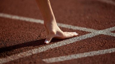 Yakın plan bayan sporcu eli başlangıç çizgisinde gerginlik ve odaklanma ile koşuya hazır. Konsantrasyon, beklenti, patlayıcı enerji, kararlılık, performans ve yarış disiplini kavramı.