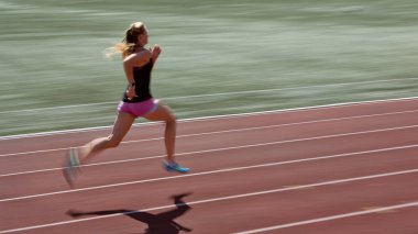 Kırmızı pistte koşan, geçmişi bulanık, patlayıcı adımlar ve güç gösteren bir bayan atlet. Zirve hızı, hareketli atlet, kararlılık ve dinamik sürat eylemi kavramı.