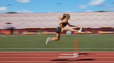 Stadyum pistindeki yarış sırasında kadın engellinin dinamik görüntüsü bulanıklaştı. Atletizm, hız, kararlılık, ırk yarışması ve açık hava performansı kavramı.