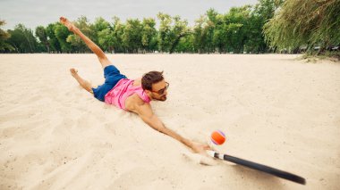 Kumsalda kayan erkek atlet, kumsalda topa uzanıyor. Spor dayanıklılığı, çaba psikolojisi, fitness yaşam tarzı ve duygusal kararlılık kavramı.