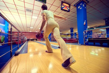 Bowlingci, mor top ve eski tasarım ile ahşap şeritte fırlatmaya hazırlanıyor. Beklenti kavramı, performanstan önce konsantrasyon, kapalı mekan kültürü, psikolojik gerilim ve spor adanmışlığı