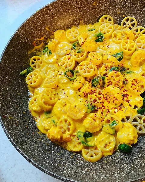 pasta dish in a pan, pasta circles, creamy pumpkin sauce, shrimps, green pepper and paprika powder, creamy pasta with sauce
