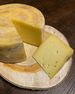 yuvarlak peynir, ev yapımı emmental peynir, delikli peynir, tahta tahtada dilimlenmiş peynir.