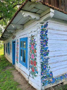 old old wooden house, painted white and decorated with drawings country house, historic country house, side of the house painted with flowers, decorative facade, Zalipie village, Poland 