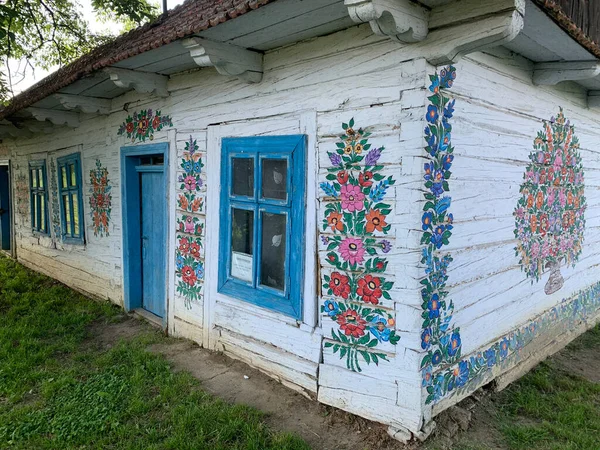 old old wooden house, painted white and decorated with drawings country house, historic country house, side of the house painted with flowers, decorative facade, Zalipie village, Poland