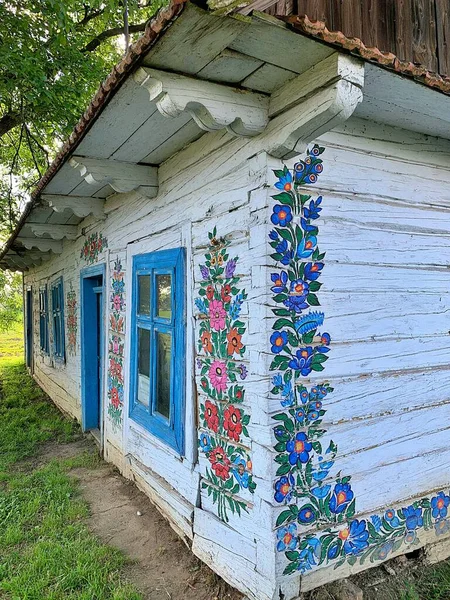 old old wooden house, painted white and decorated with drawings country house, historic country house, side of the house painted with flowers, decorative facade, Zalipie village, Poland