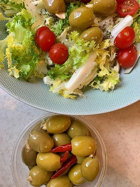vegetables, a bowl of green olives, a bowl of lettuce and tomatoes, spicy green olives, olives stuffed with almonds, vegetable side dishes