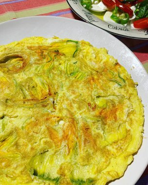 omelette with zucchini flowers, fresh egg omelette, salad with tomatoes and mozzarella, breakfast dish plate