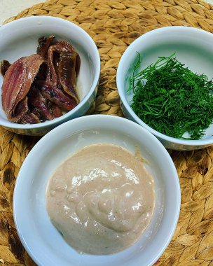 small bowls with appetizers, chopped dill, small fillets of salty fish, mayonnaise sauce, additives, ingredients for dishes in containers