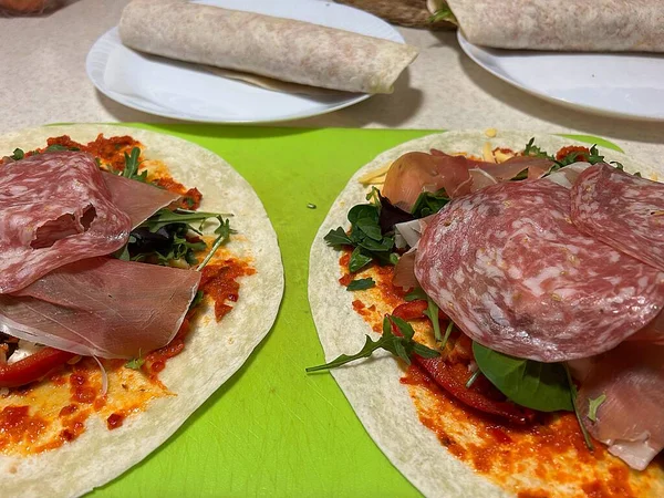 Tortilla, salam, çiğ Parma jambonu, roka, ayvar biberi sosu, tortillaların üzerine ürün koymak, tortilla sarmak