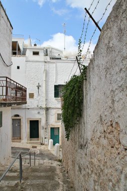 Ostuni 'de bir sokak, beyaz evler, bir İtalyan şehrinin parlak binaları, Apuglia bölgesi, binaların kabloları