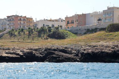  Polignano bir Mare sahili, deniz manzarası, tekne gezisi, Puglia bölgesi, güney İtalya, deniz kenarında şehir, güney İtalya 'da basit beyaz binalar, kıyıda düz kayalar.