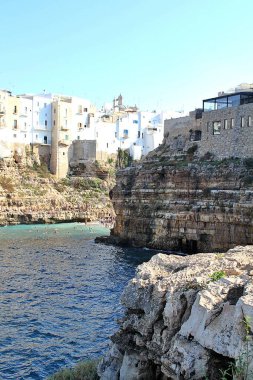  Deniz kenarındaki kayalar, deniz kıyısındaki kayalara inşa edilmiş binalar Polignano a Mare, kayalık kıyı, turkuaz su, deniz kenarındaki kayalar, deniz kıyısındaki kayaların üzerine inşa edilmiş binalar, turkuvaz suyu, denizde yıkanan insanlar.