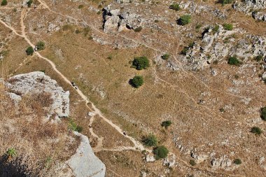 Kayalara oyulmuş mağaralar, eski bir şehrin kalıntıları, oyulmuş çukurları, dağları, tepeler arasındaki yolu olan tepeler.